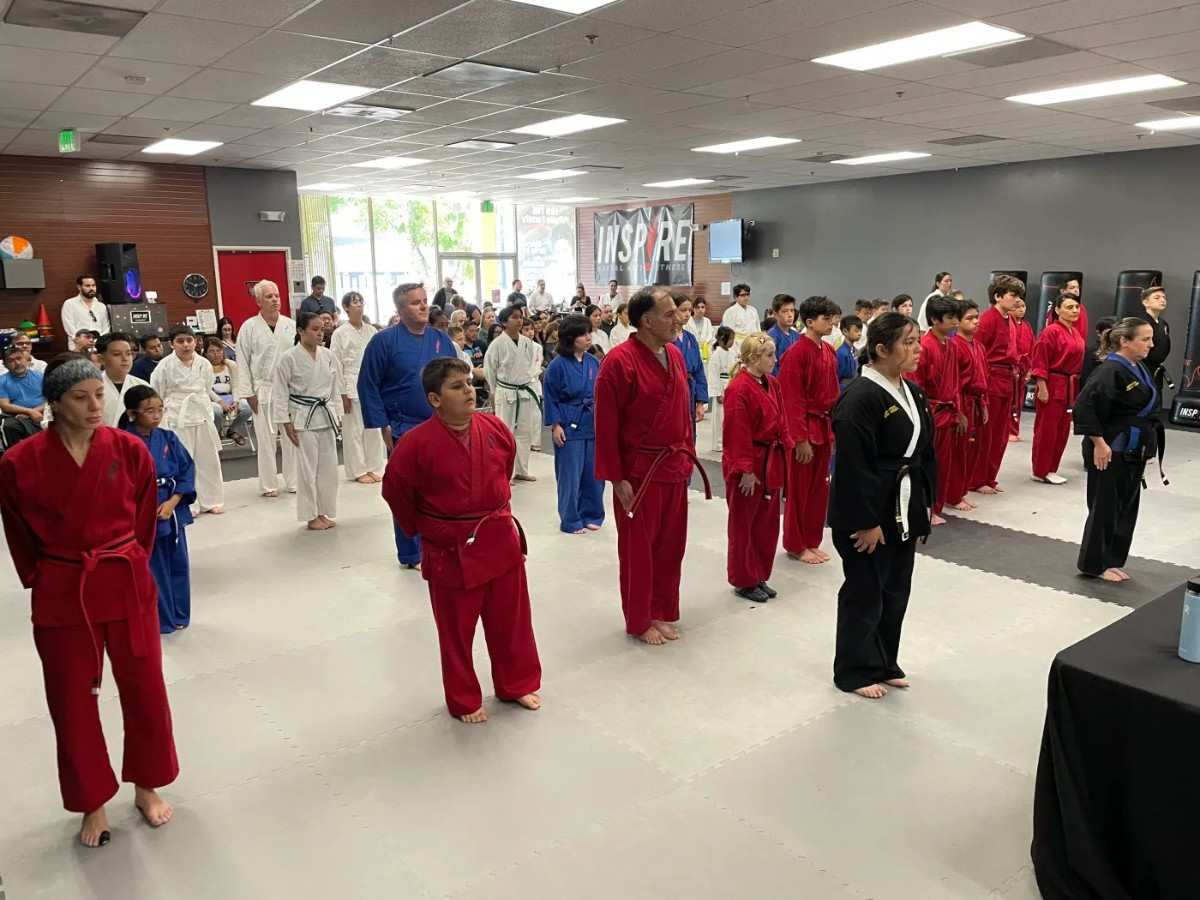 Large group standing in formation during a family self defense class inside a martial arts studio.