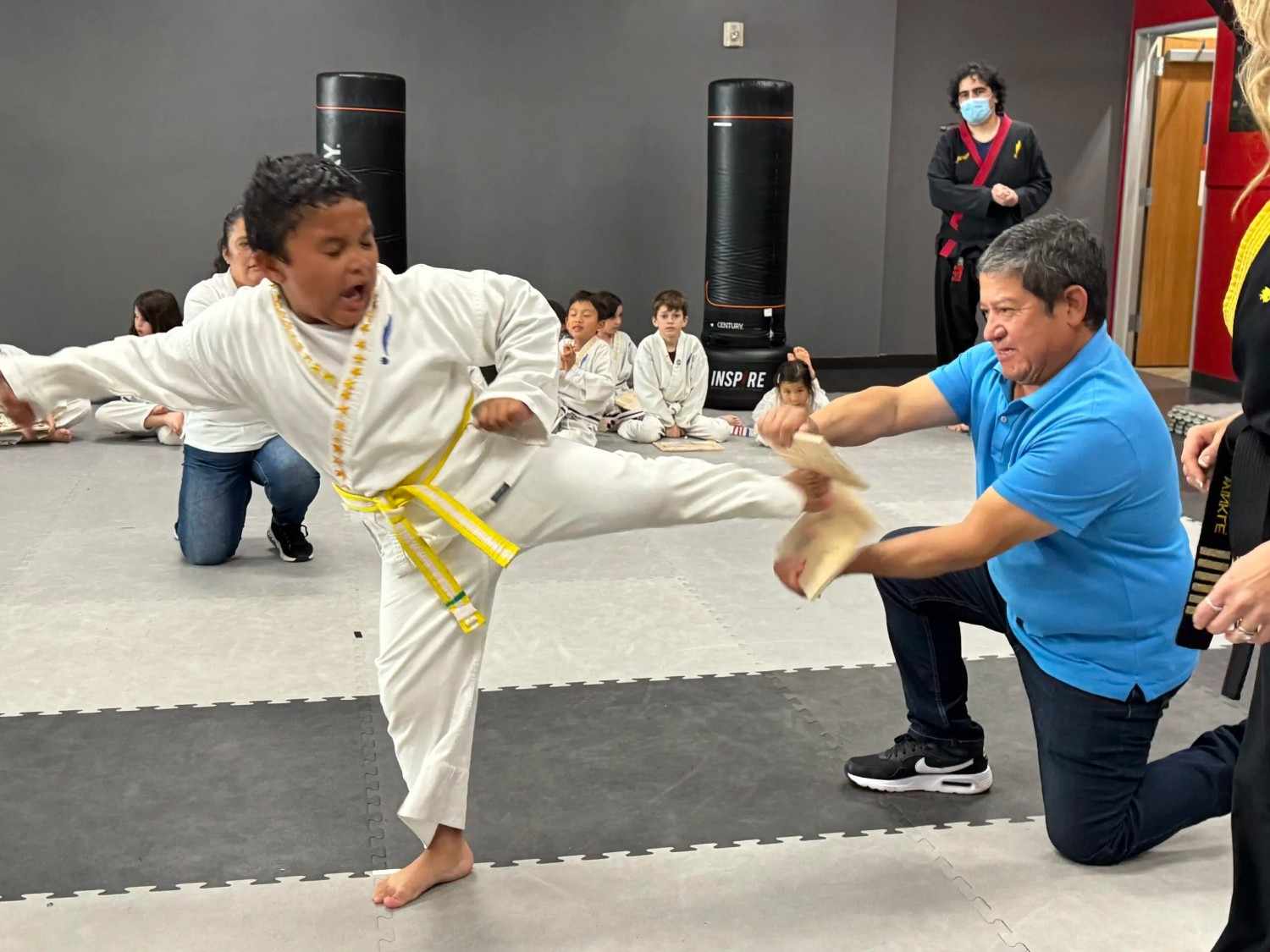 A student kicking through a wood panel during one of his self defense classes