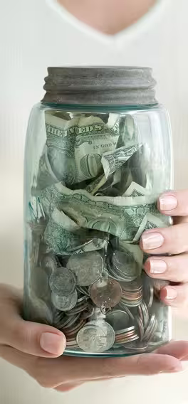 A woman holding a jar full of money.