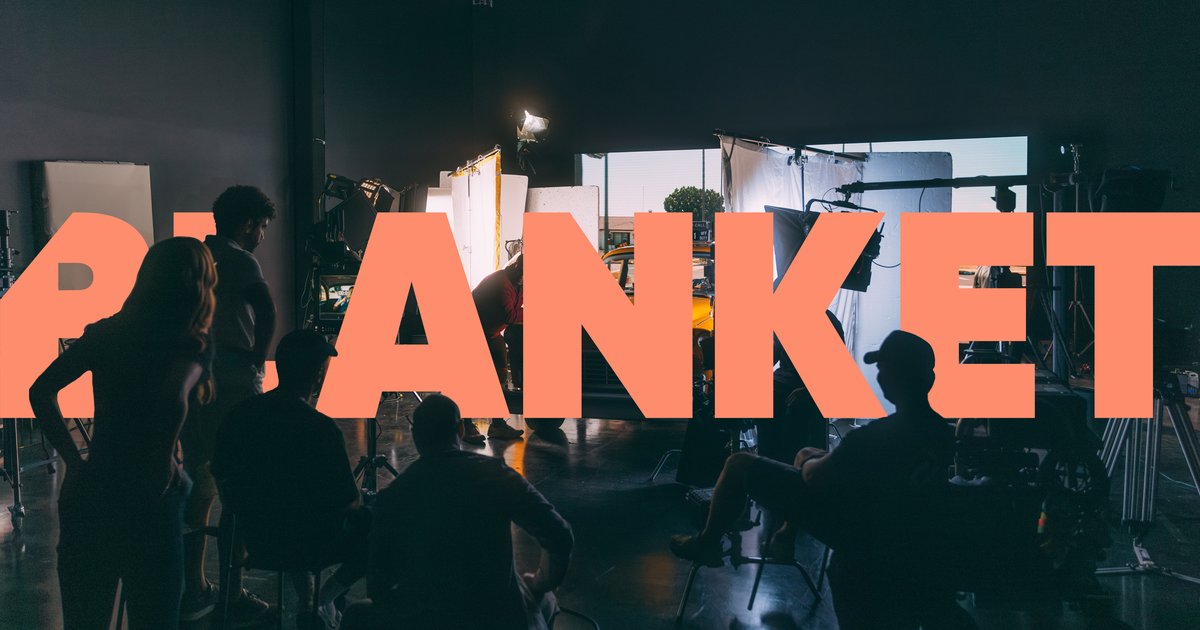 Silhouettes of a film crew working in a studio with bright lights and camera equipment.