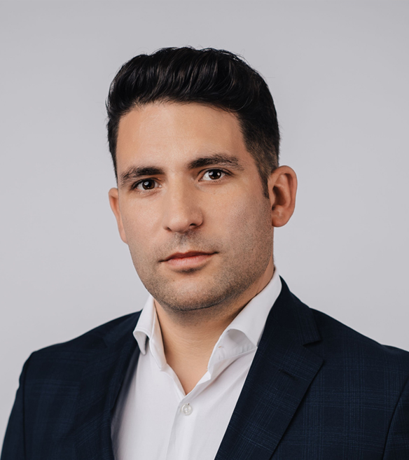 Young man in a dark jacket and white shirt against a light background