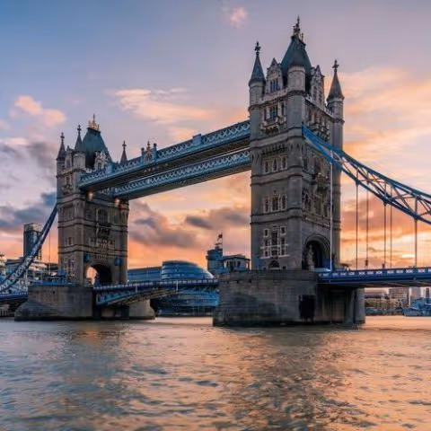 The raised section of Tower Bridge in London at sunset over the River Thames.