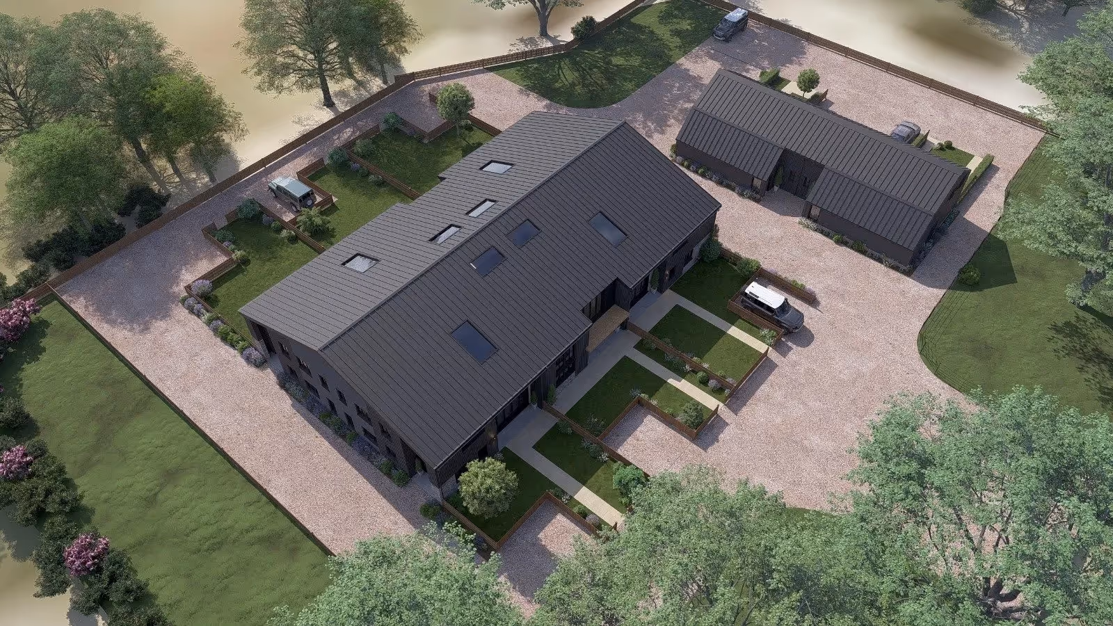 Aerial view of a modern residential complex with a large main building and a smaller outbuilding surrounded by trees and grass.