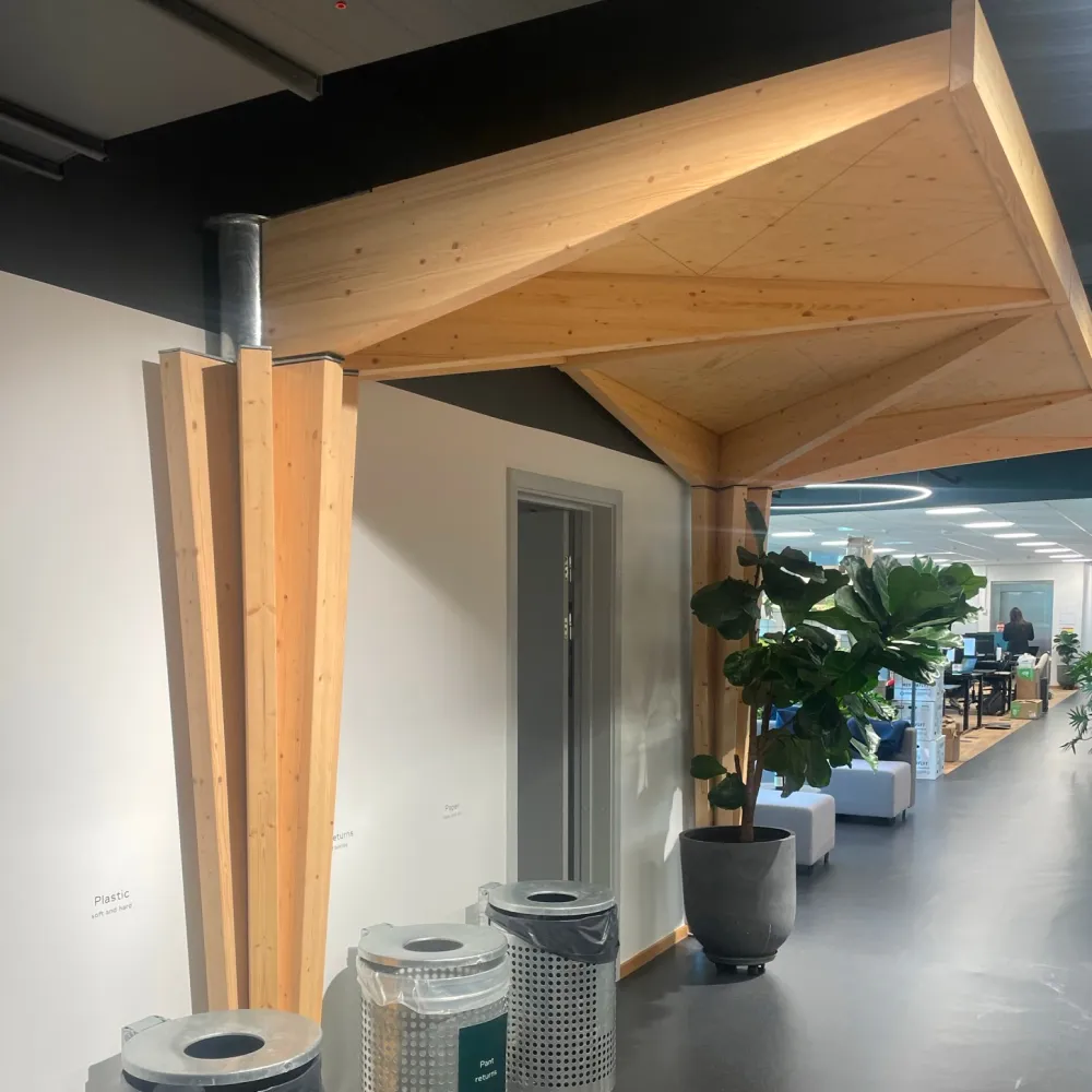 Specialdesignet søjlebeklædning i metal og træ, leveret af faglært smed til moderne kontormiljø.