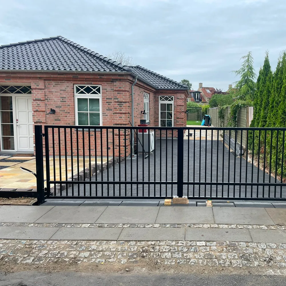 Robust sortlakeret skydeport monteret ved indkørsel til privat ejendom af din smed.