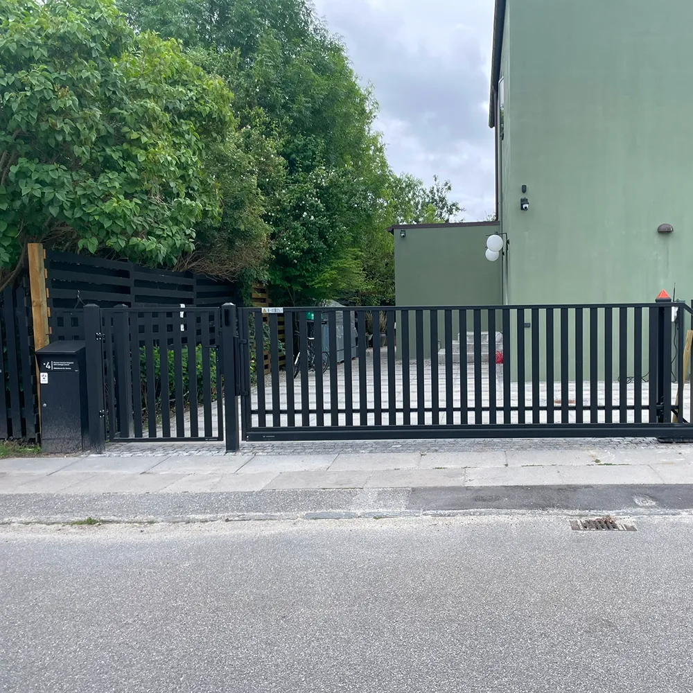 Bred sort metalport monteret ved erhvervsejendom i Storkøbenhavn for optimal sikring.