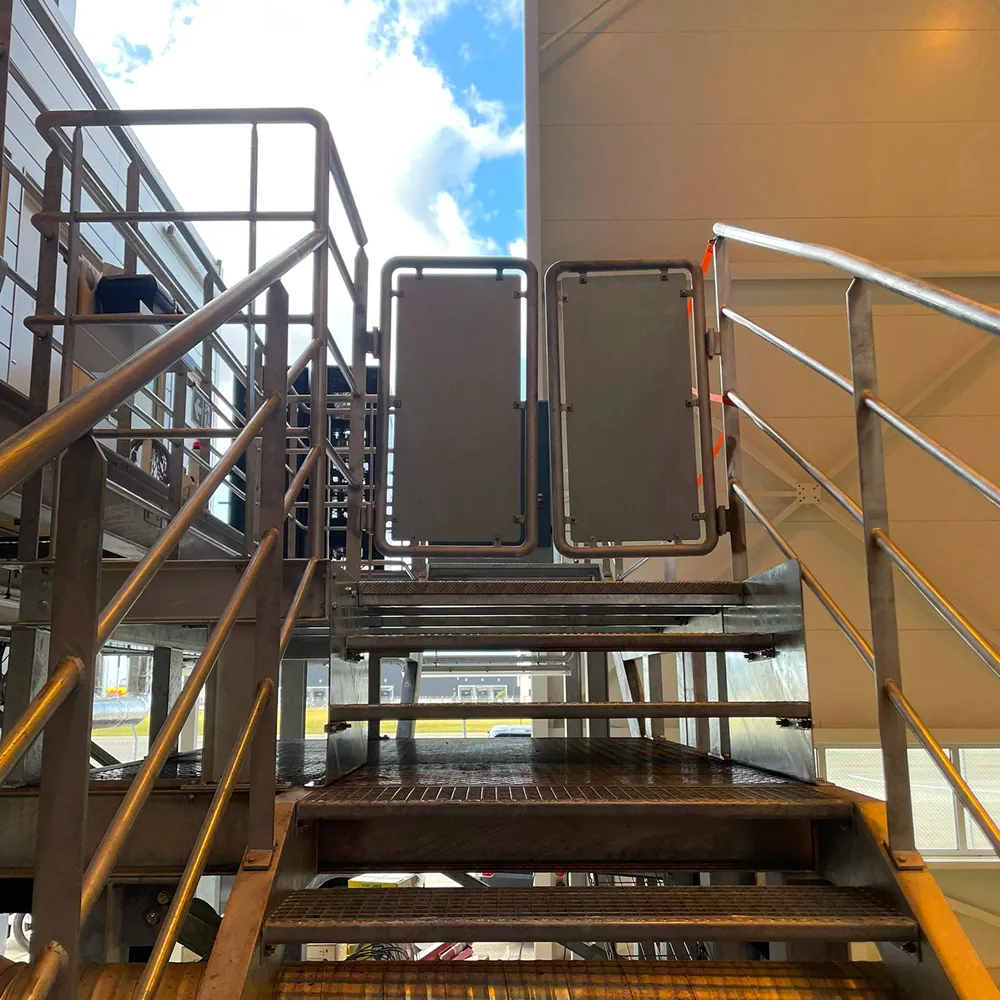 Robust industritrappe med værn og låge, leveret af jeres lokale smedeværksted.