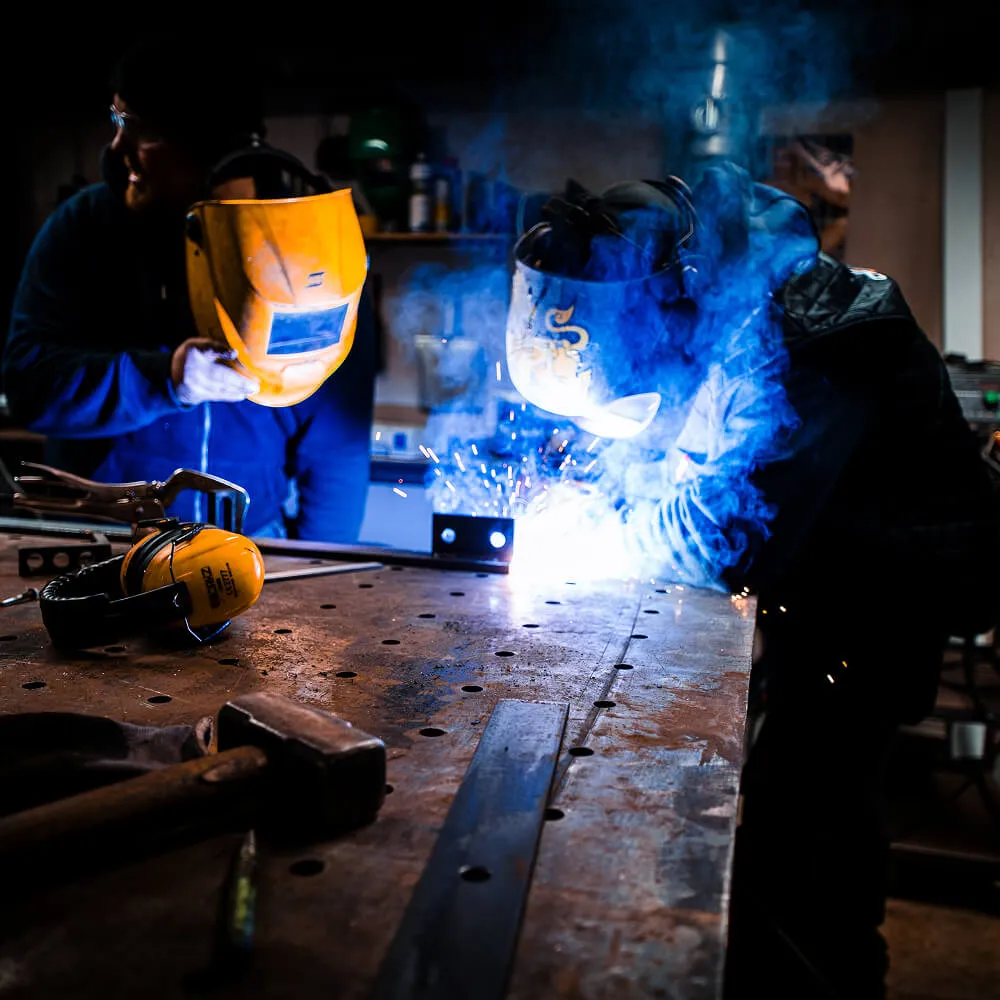 Professionel smed udfører præcisionssvejsning på en stålkonstruktion.