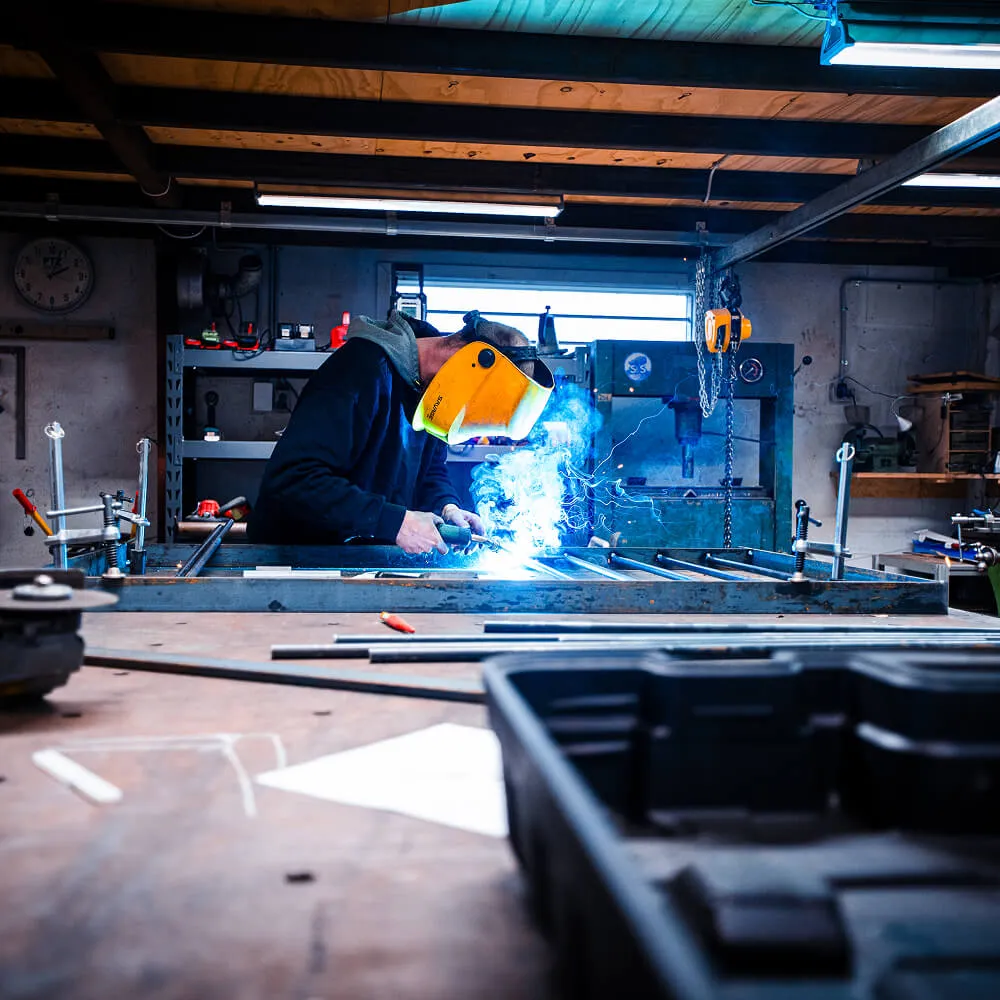 En CMP Metal-smed bærer beskyttelsesudstyr under præcisionssvejsning af en metalramme på værksted i København.