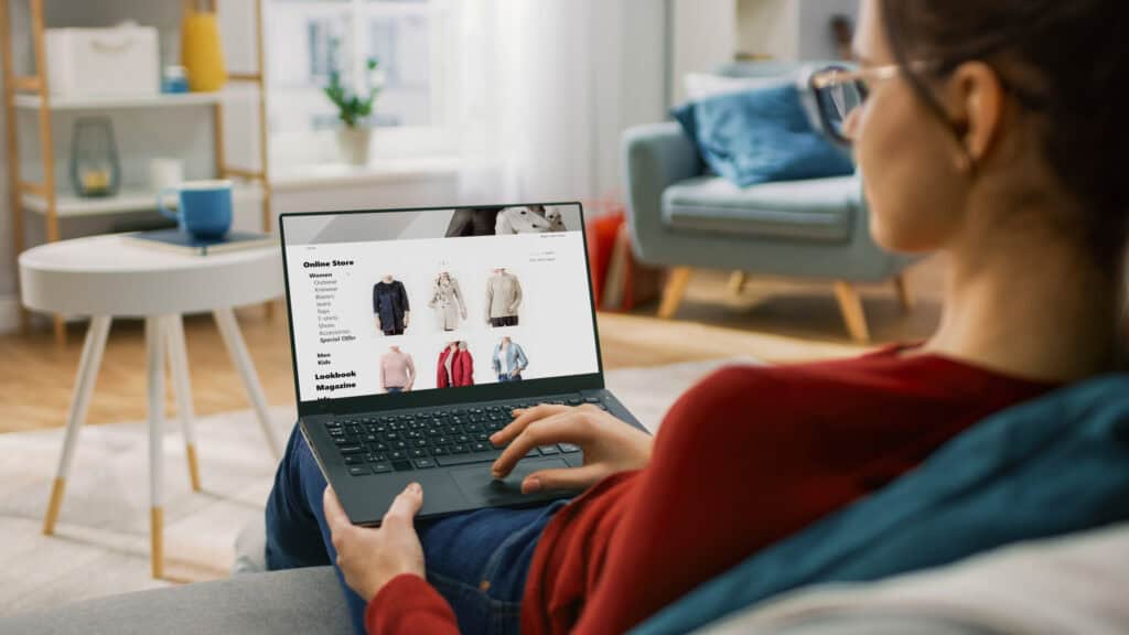 Woman browsing online clothing store on laptop in modern living room