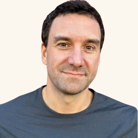 Middle-aged man with dark hair wearing blue shirt against neutral background