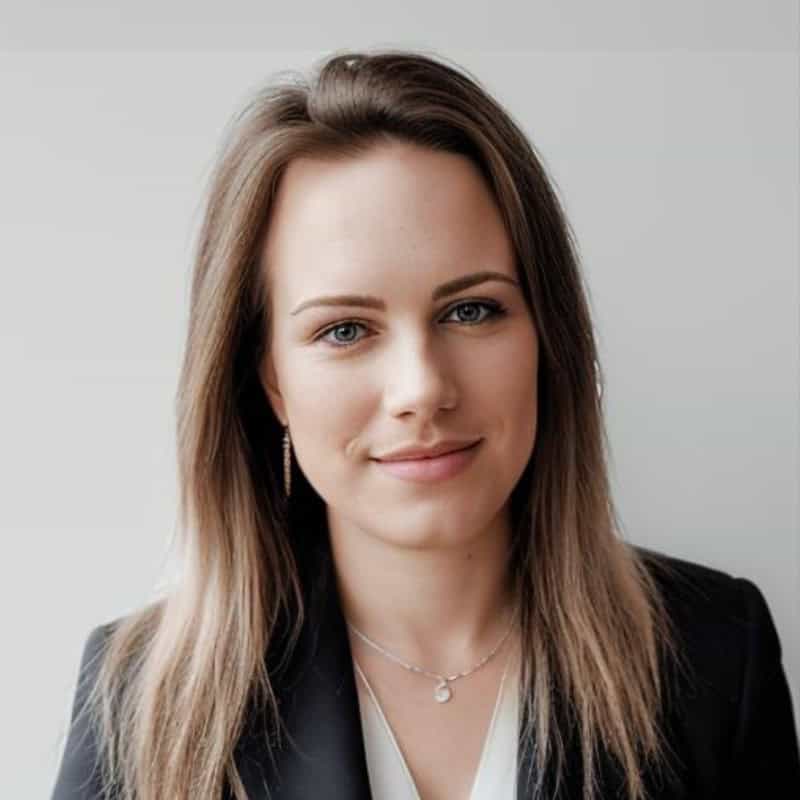 Professional headshot of a woman with long brown hair and subtle smile against gray background