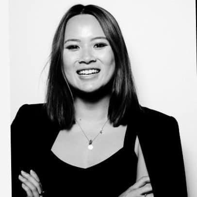 Smiling woman with shoulder-length black hair wearing dark blazer, black and white portrait photo