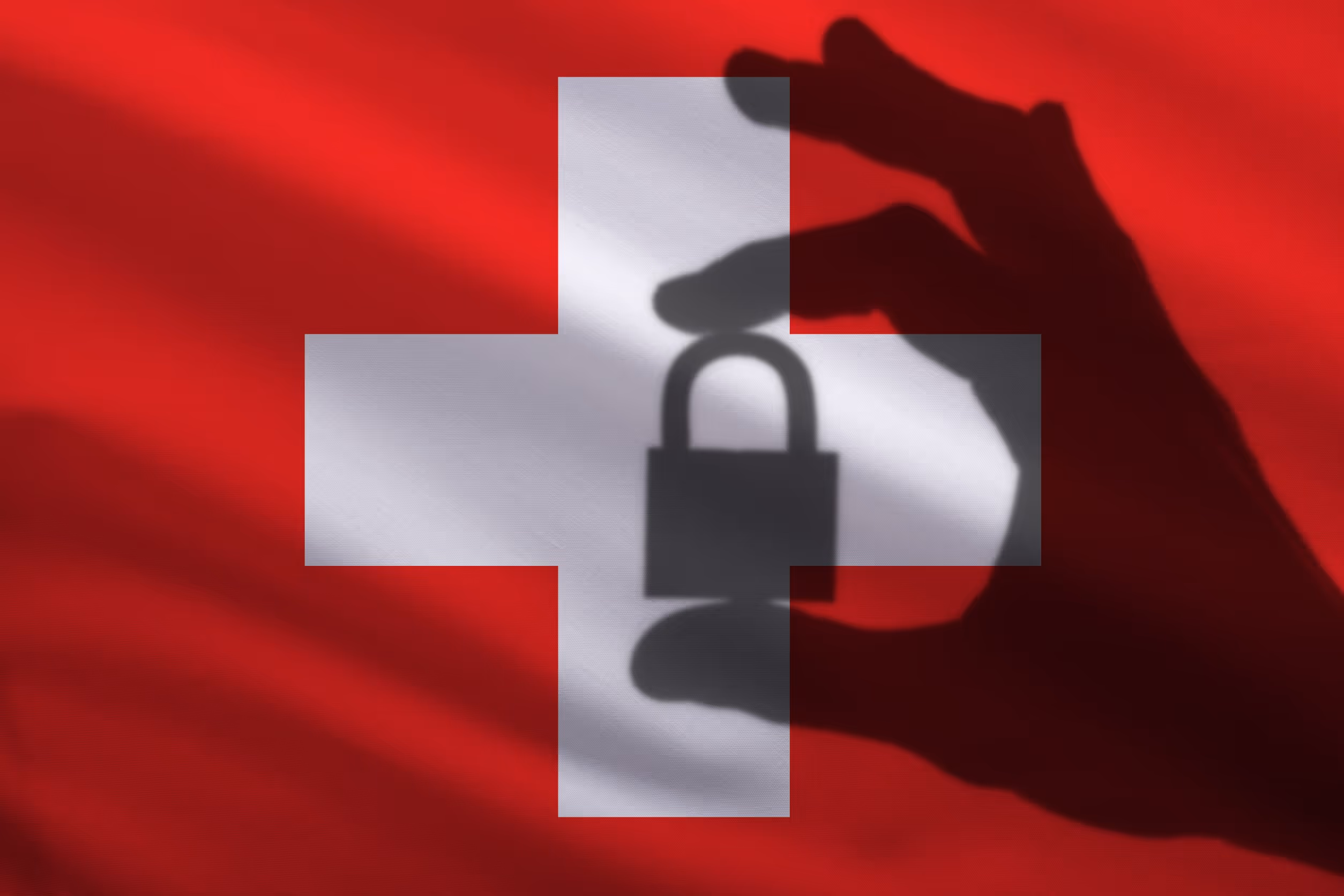 Symbolbild: Hand schützt Vorhängeschloss als Schatten vor Schweizer Flagge.
