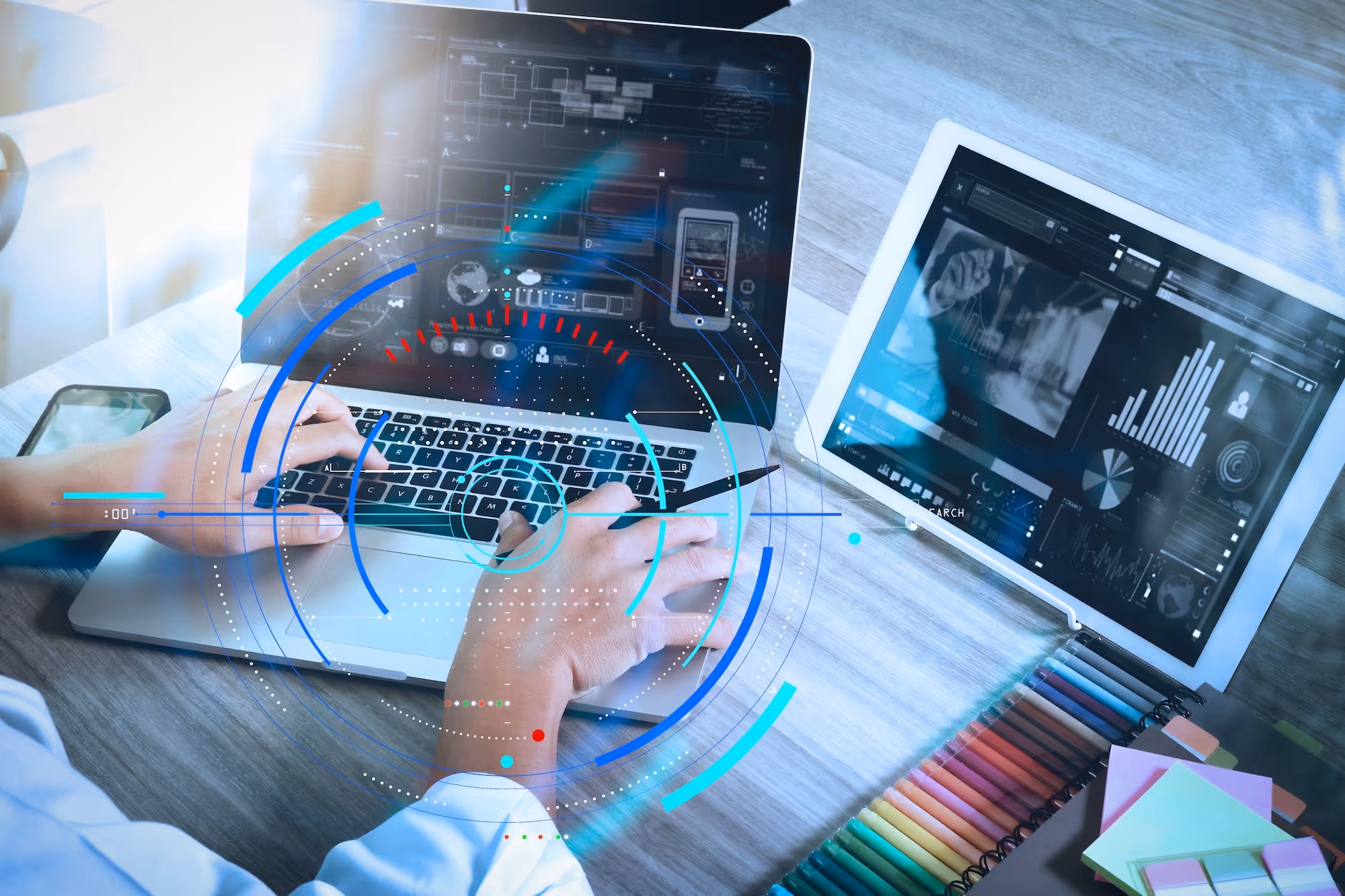 Person arbeitet an Laptop und Tablet, überlagert von einer leuchtenden Daten-Grafik.