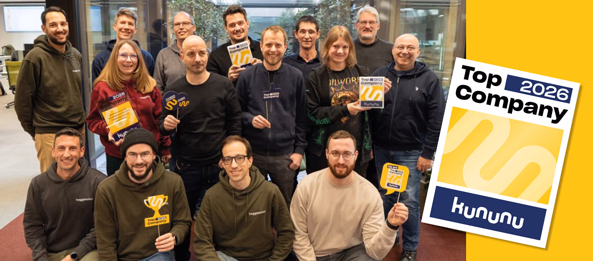 Lachendes Baggenstos-Team mit Pokalen und Urkunden im Büro, daneben kununu Top Company 2026 Siegel.