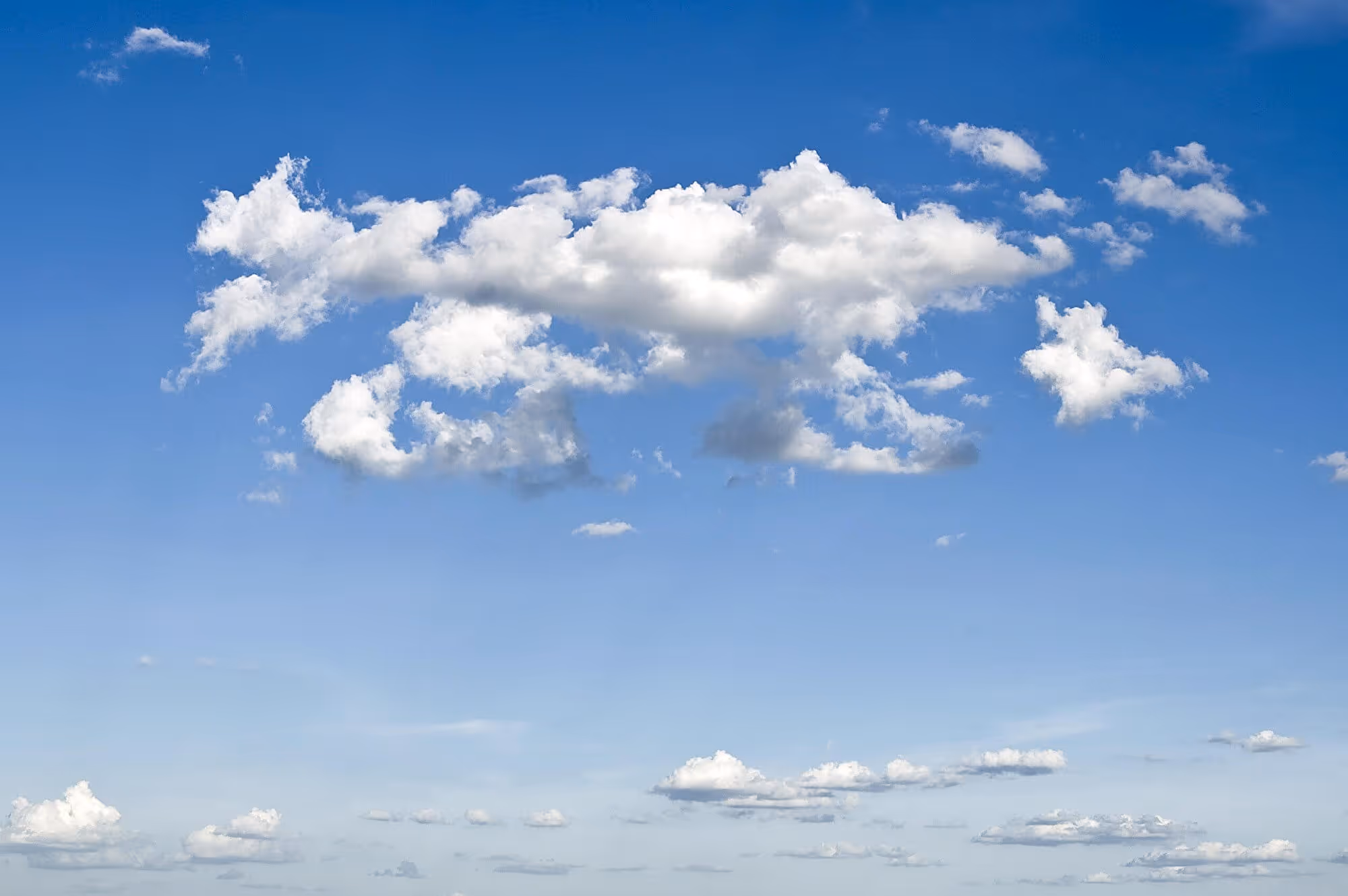 Weisse Schäfchenwolken vor blauem Himmel an einem sonnigen Tag.