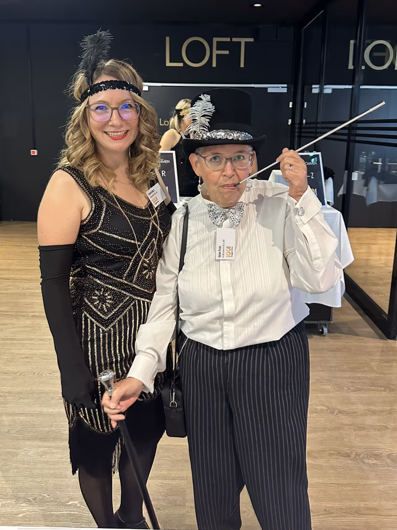 Frau im Flapper-Kleid und Mann mit Zylinder posieren im 20er-Jahre-Kostüm nebeneinander.