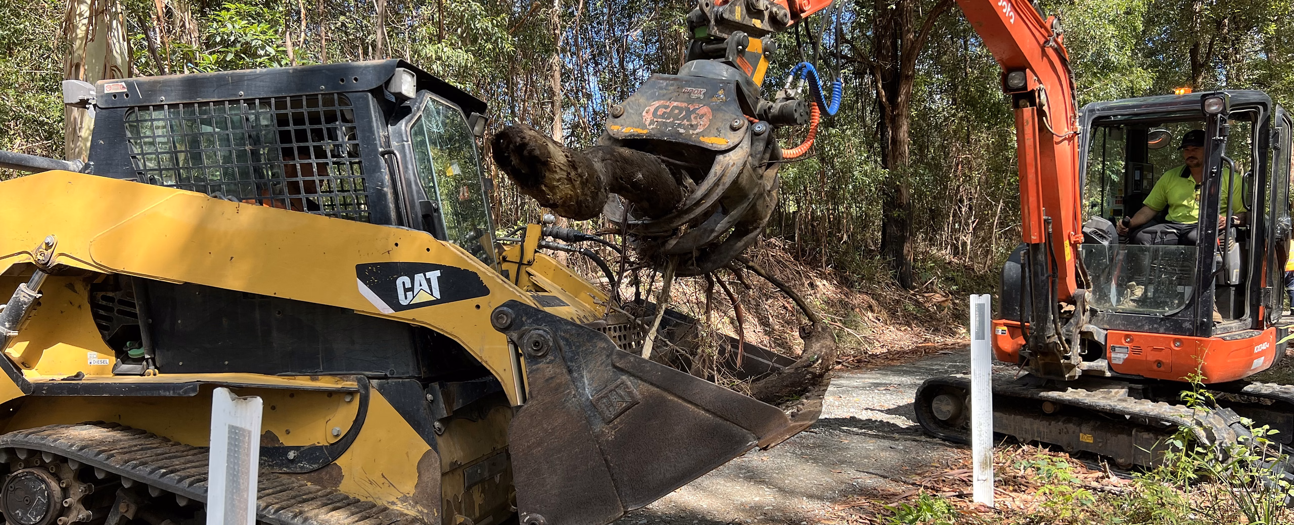 CAT tracked loader and excavator clearing scrub together on a bush acreage block