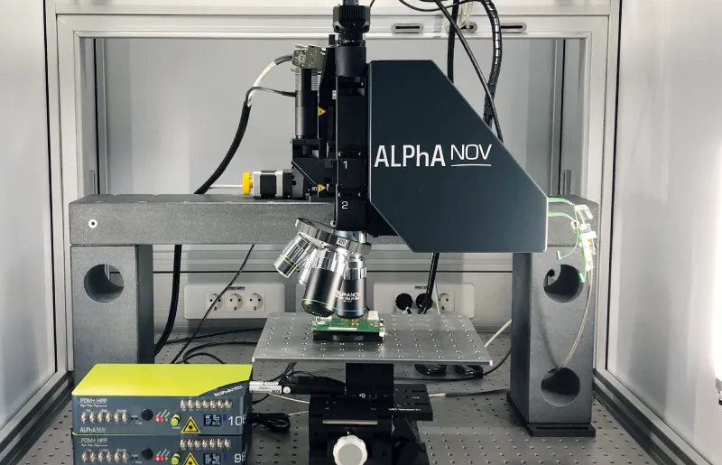 ALPhANOV laser microscope station with mounted lenses and electronic control unit on a lab workbench.