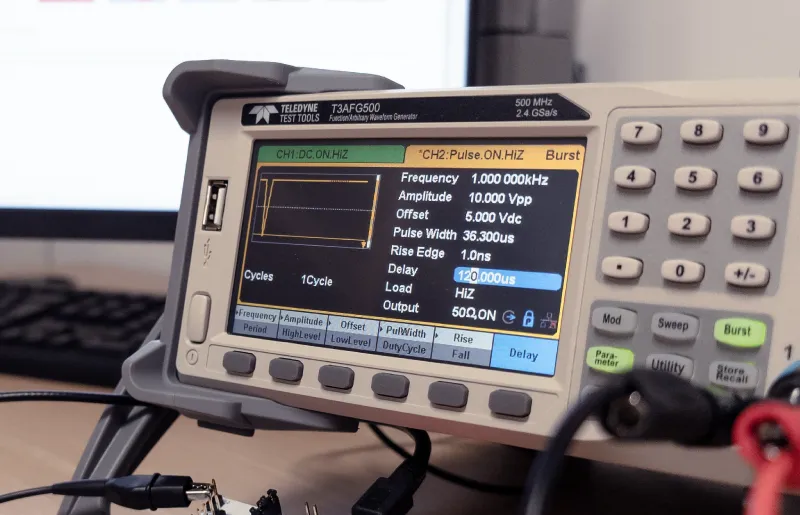 Teledyne T3AFG500 function/waveform generator displaying pulse settings including frequency 1 MHz, amplitude 10 Vpp, offset 5 Vdc, pulse width 36.3 µs, and delay 120 µs.
