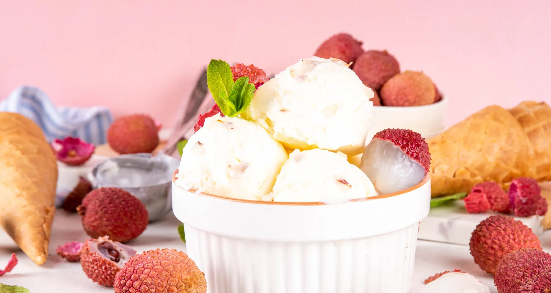 Boules de glace litchi avec litchis frais et feuilles de menthe dans un bol blanc.