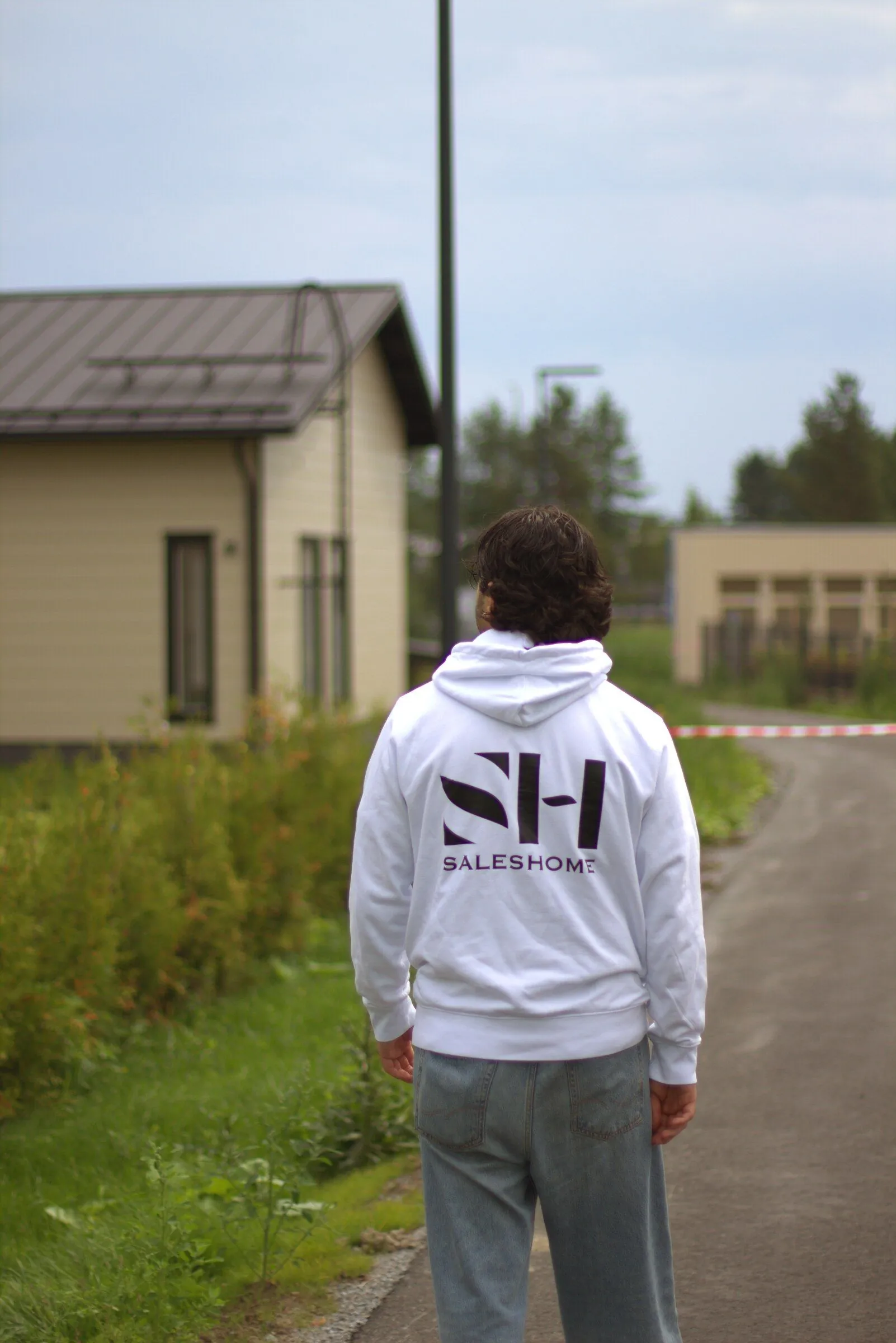 Saleshomen myyjä SH-hupparissa selkä kameraan päin.