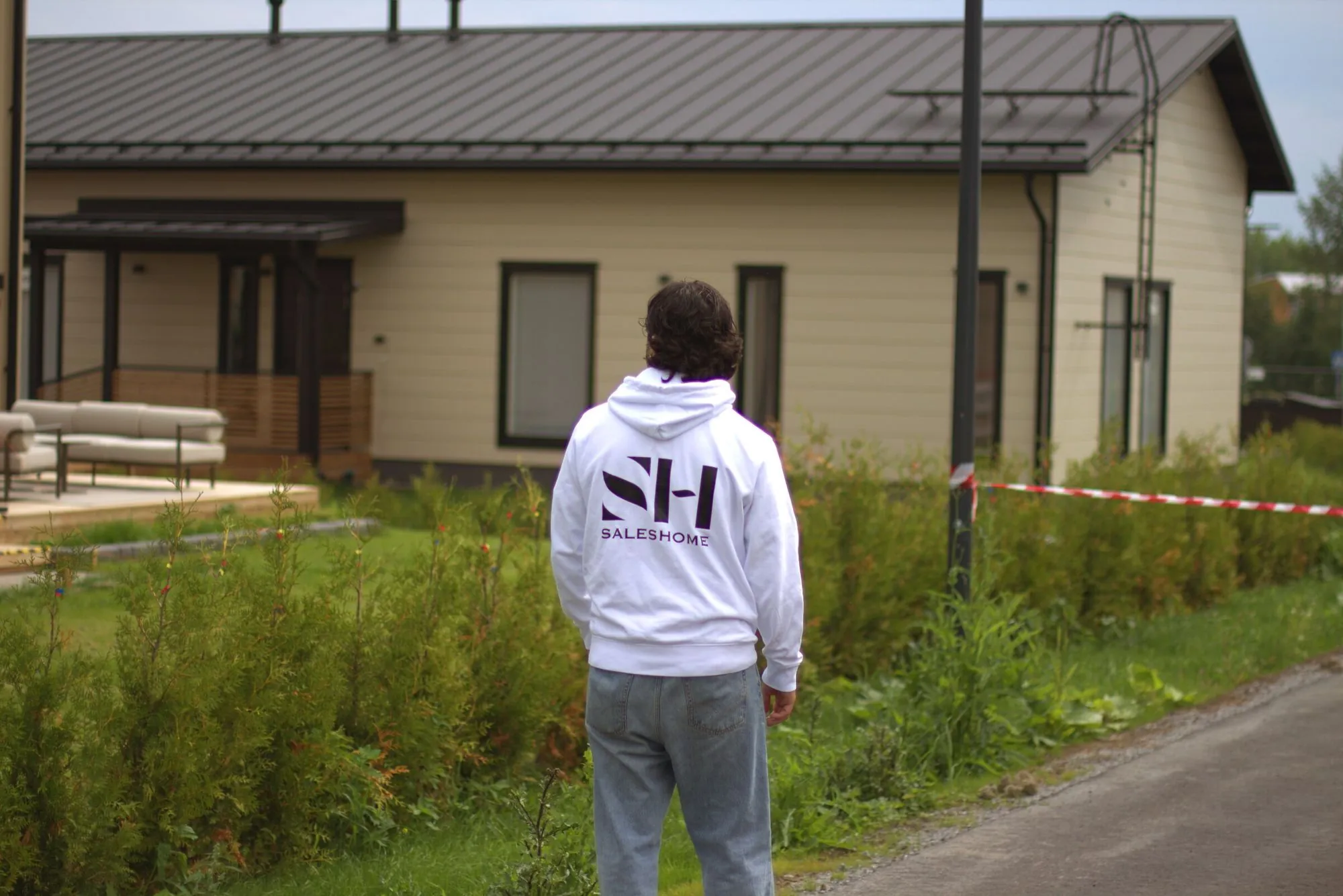 Ovimyynti: Saleshomen myyjä SH-hupparissa omakotitalon pihalla.