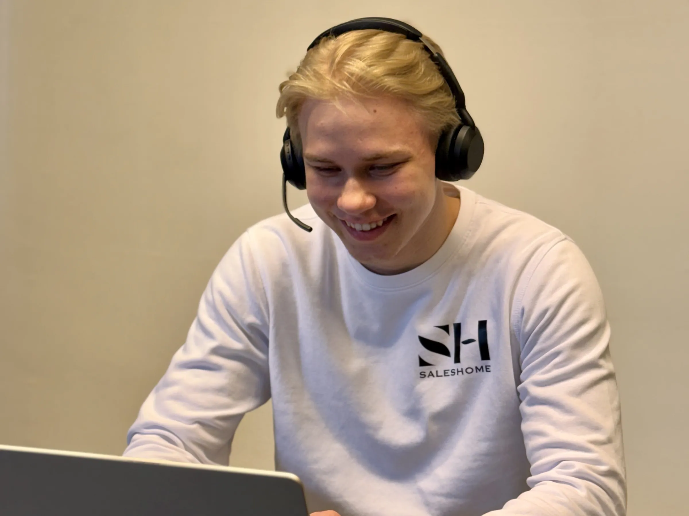 Saleshomen myyjä nauraa puhelun aikana kuulokkeet päässä