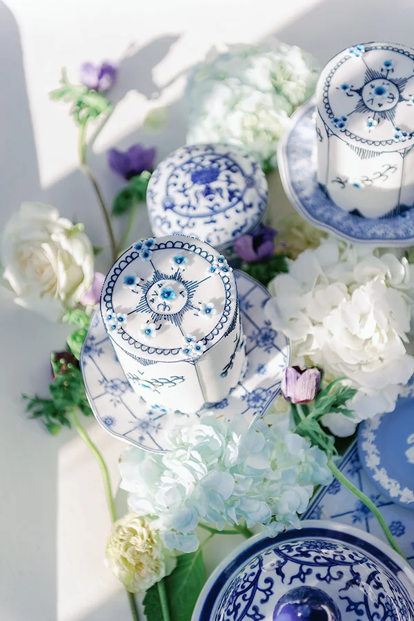 Decorative blue and white ceramic containers surrounded by white and purple flowers.