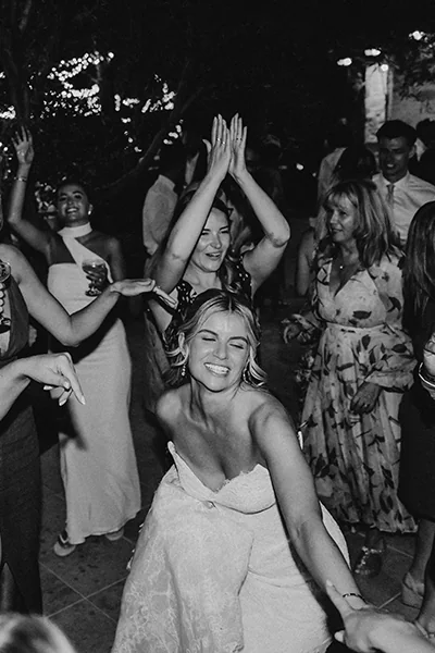 Bride in a wedding dress dancing joyfully with guests in a lively celebration.