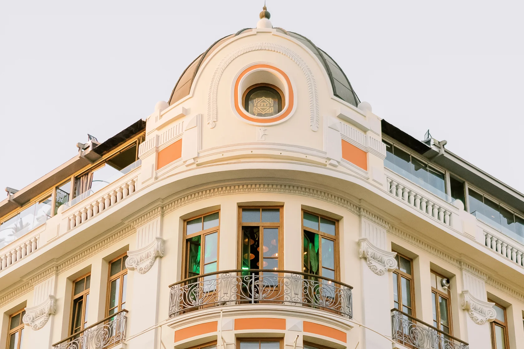 Ornate corner of a historic building with cream and orange facade, wooden framed windows, and decorative wrought iron balconies.