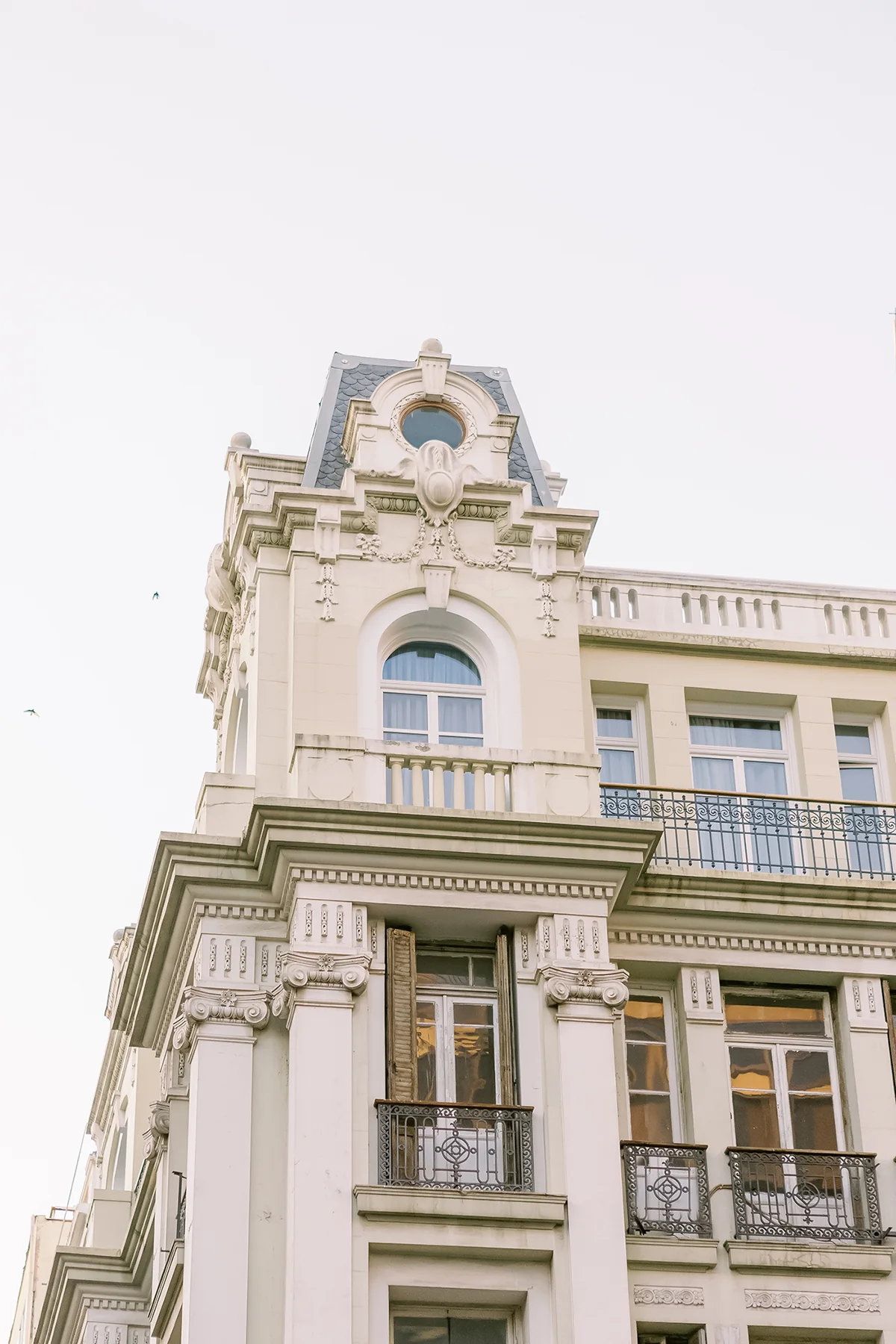 Ornate beige building with decorative architectural details, arched windows, and wrought iron balconies.