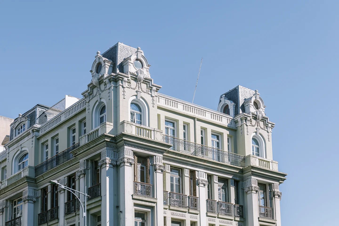Ornate historic building corner with decorative stonework and arched windows against clear blue sky.