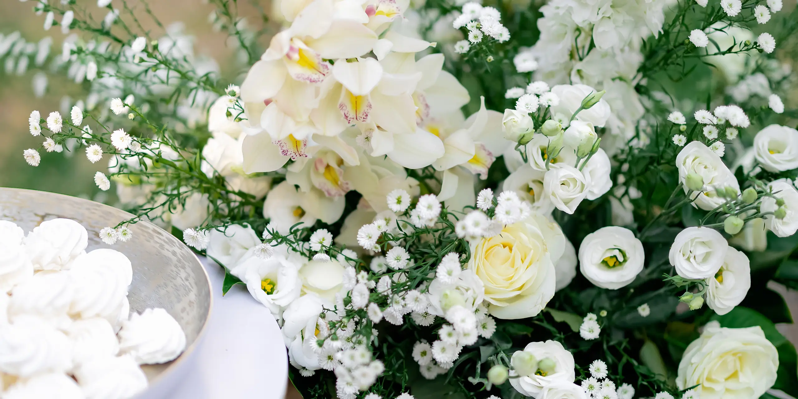 Close-up of white flowers including roses, orchids, and small blossoms with green foliage.