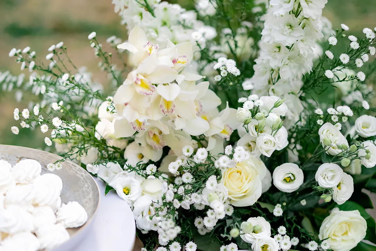 Elegant bouquet of white flowers including roses, orchids, and baby's breath on a table.