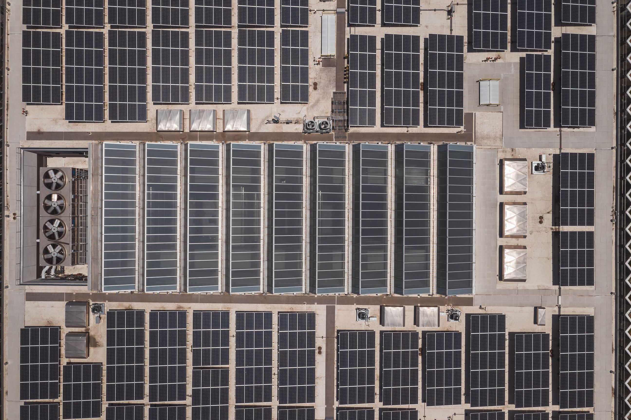 Aerial view of an industrial rooftop covered with multiple solar panels and ventilation units.
