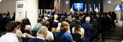Personnes assises lors d'un forum organisé dans une salle, avec un panel à l'avant.