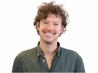 Homme souriant avec cheveux bouclés et chemise verte sur fond blanc.