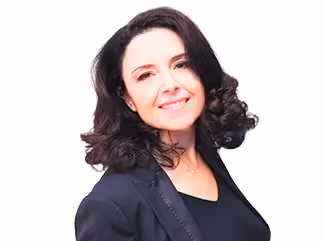Femme souriante aux cheveux bouclés portant une veste noire et un haut noir.