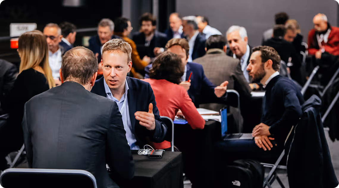 Personnes discutant en petits groupes assis autour de tables lors d'un événement professionnel.