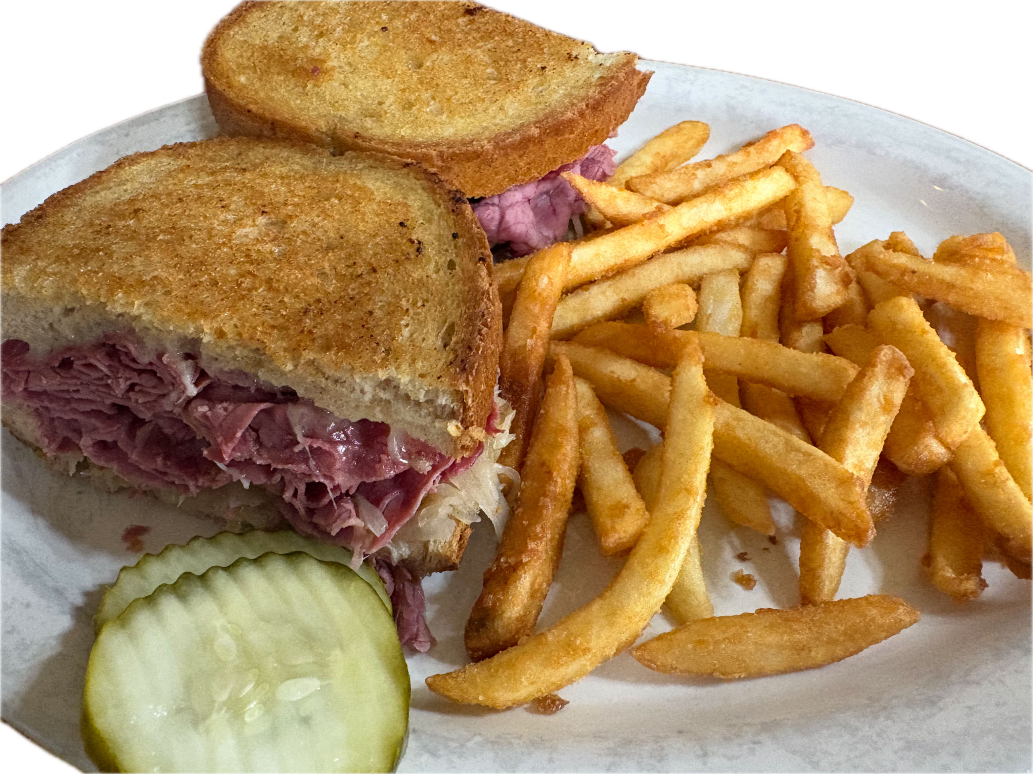 Plate with a toasted sandwich filled with meat, fries, and two pickle slices.