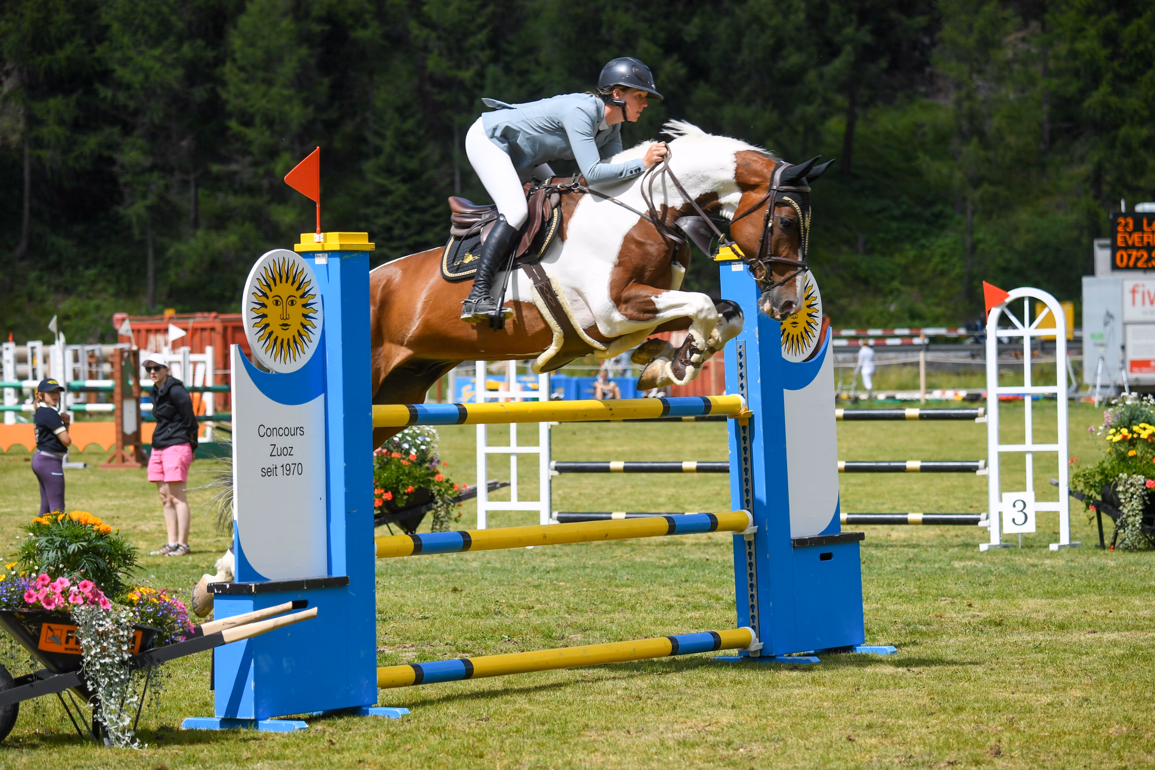 Reiterin springt mit braun-weißem Pferd über Hindernis bei Concours Zuoz.