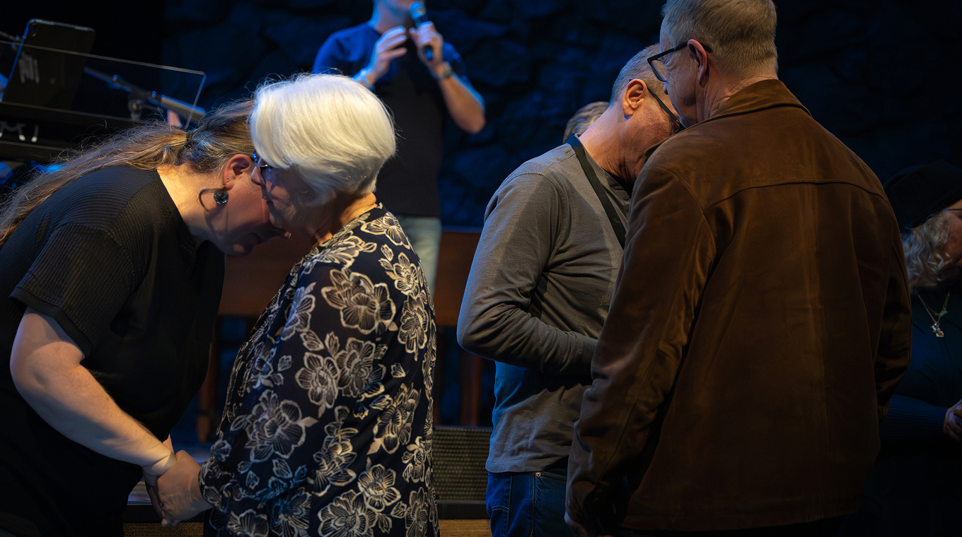 Audience standing and worshipping during a church service with musicians on stage.