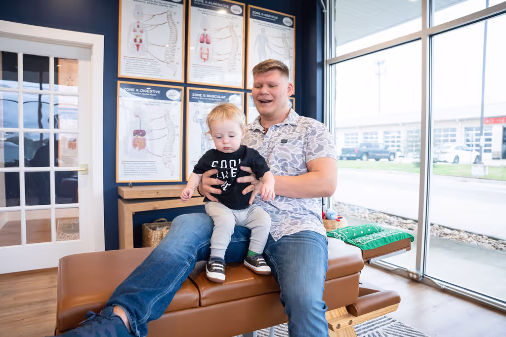 Pediatric chiropractor gently holding infant on adjustment table in Cypress