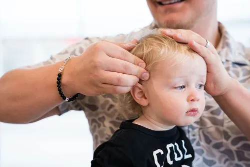 Pediatric chiropractor performing gentle cranial assessment on child