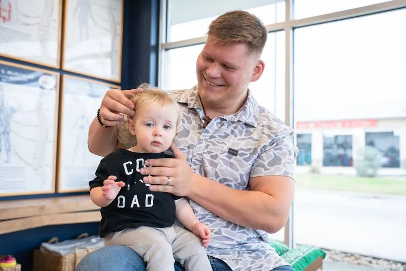 Chiropractor gently examining young child's head using Zone Technique in Cypress