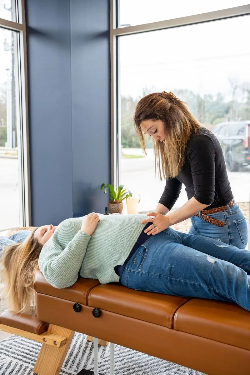 Female chiropractor examining pregnant woman's stomach for maternal wellness care