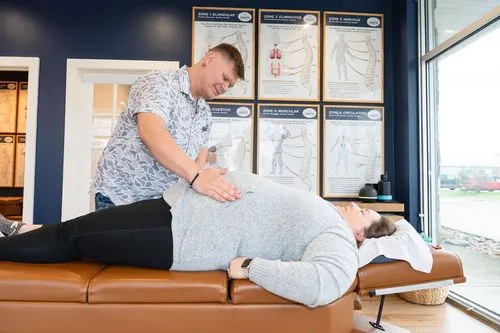 Chiropractor examining pregnant patient's stomach for prenatal wellness care