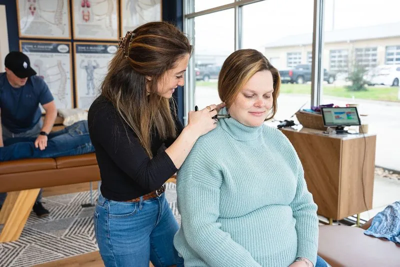 Chiropractor using activator for gentle prenatal adjustment on expecting mother